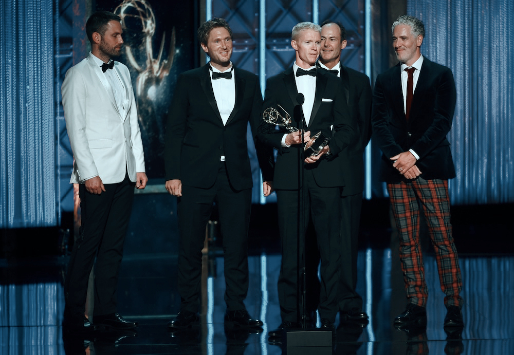 Five people in black-tie attire holding an industry award on stage, Wise Media credit
